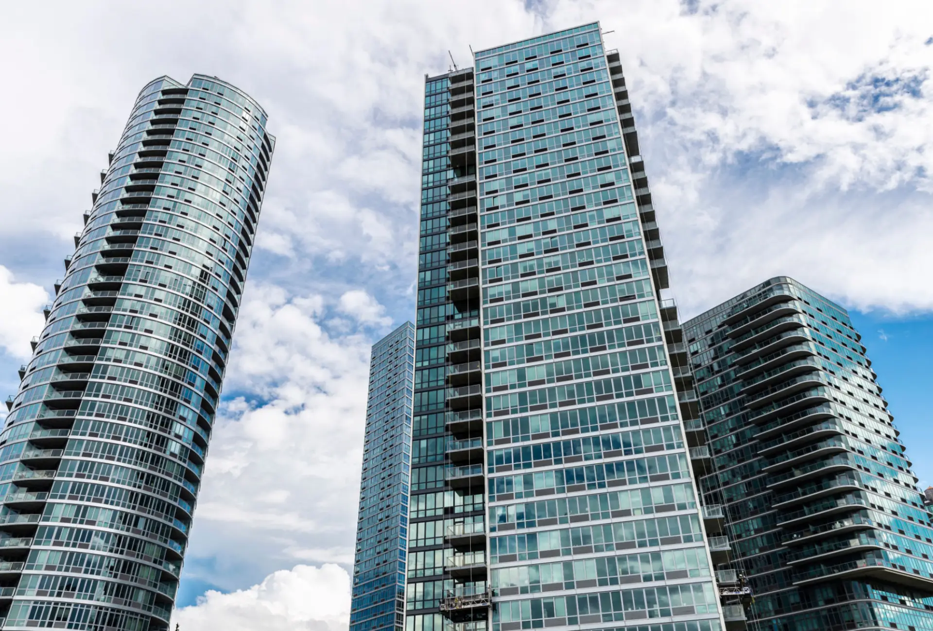 Skyscrapers with glass facades under cloudy sky.